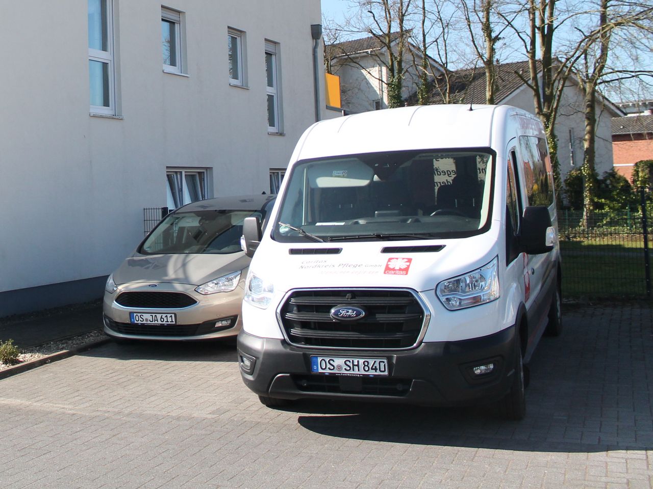 Außenansicht des Gebäudes. Ein Auto und ein Sprinter stehen daneben. 