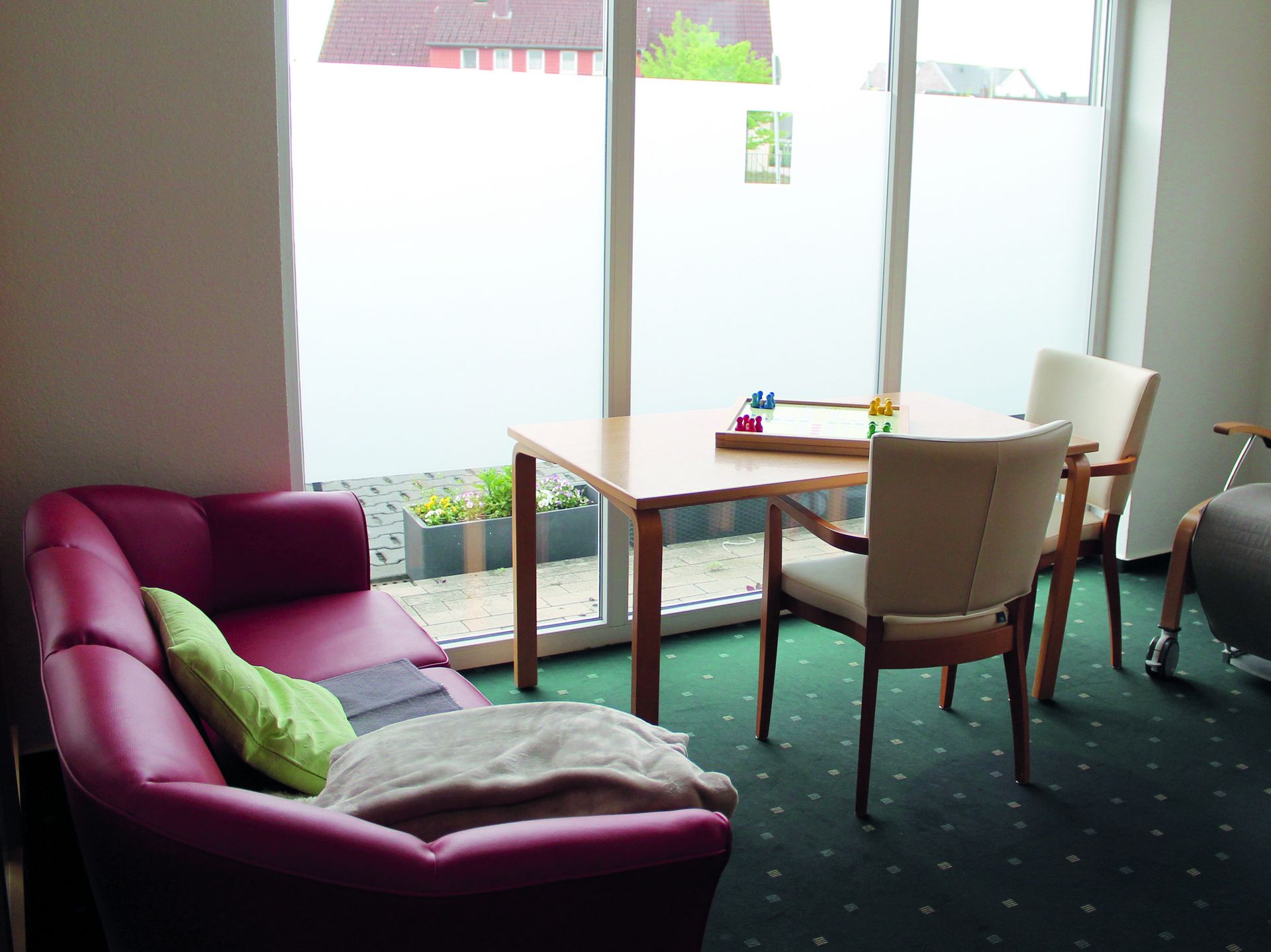 Ruheraum mit rotem Sofa und kleiner Sitzecke zum Spielen.