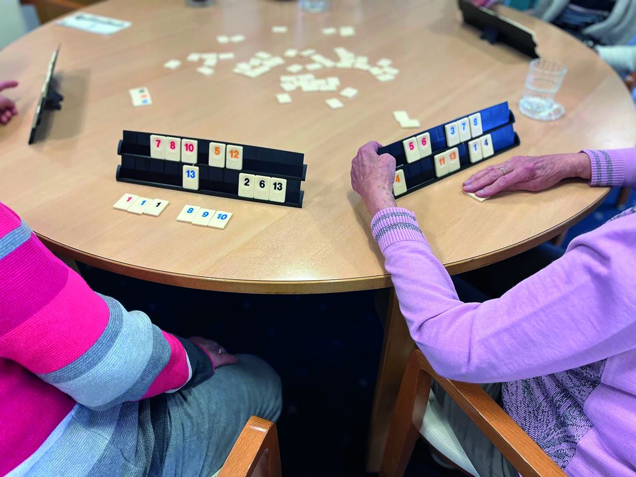 Ältere Personen sitzen am Tisch und spielen.