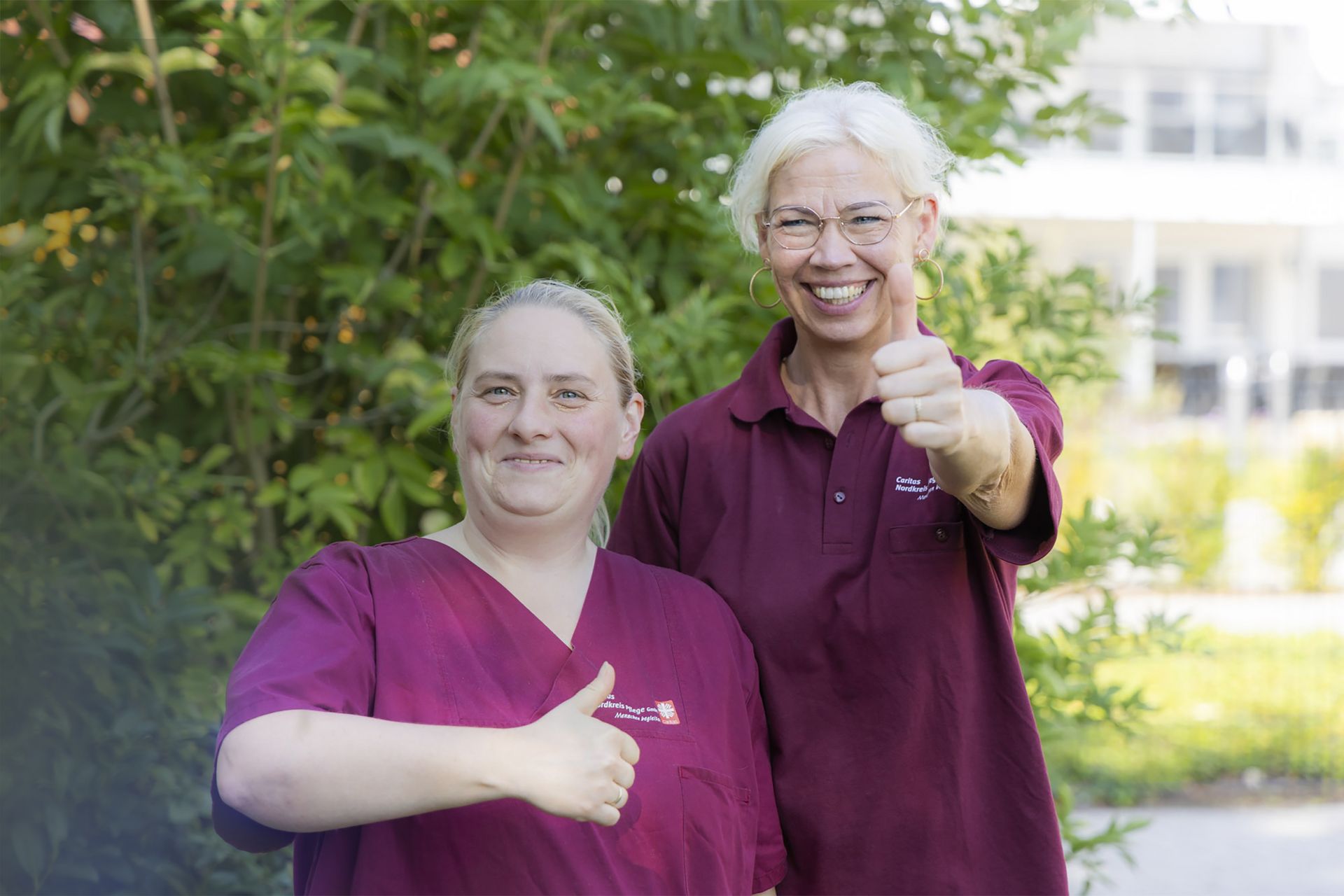 Zwei blonde Frauen gucken in die Kamera und zeigen "Daumenhoch"