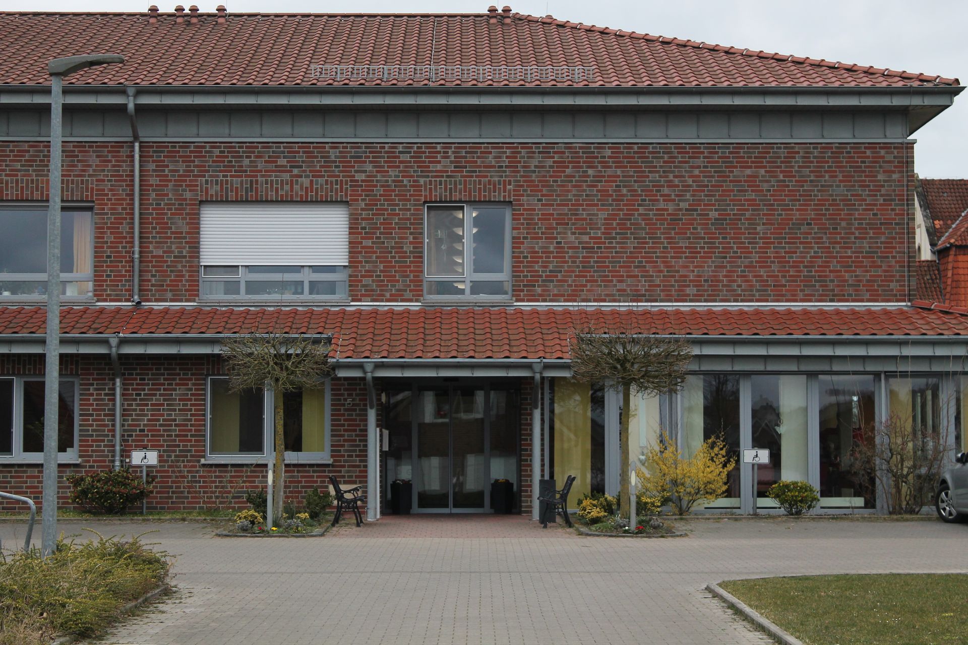 Rotes Gebäude im Hintergrund. Vorne rechts und links Rasen
