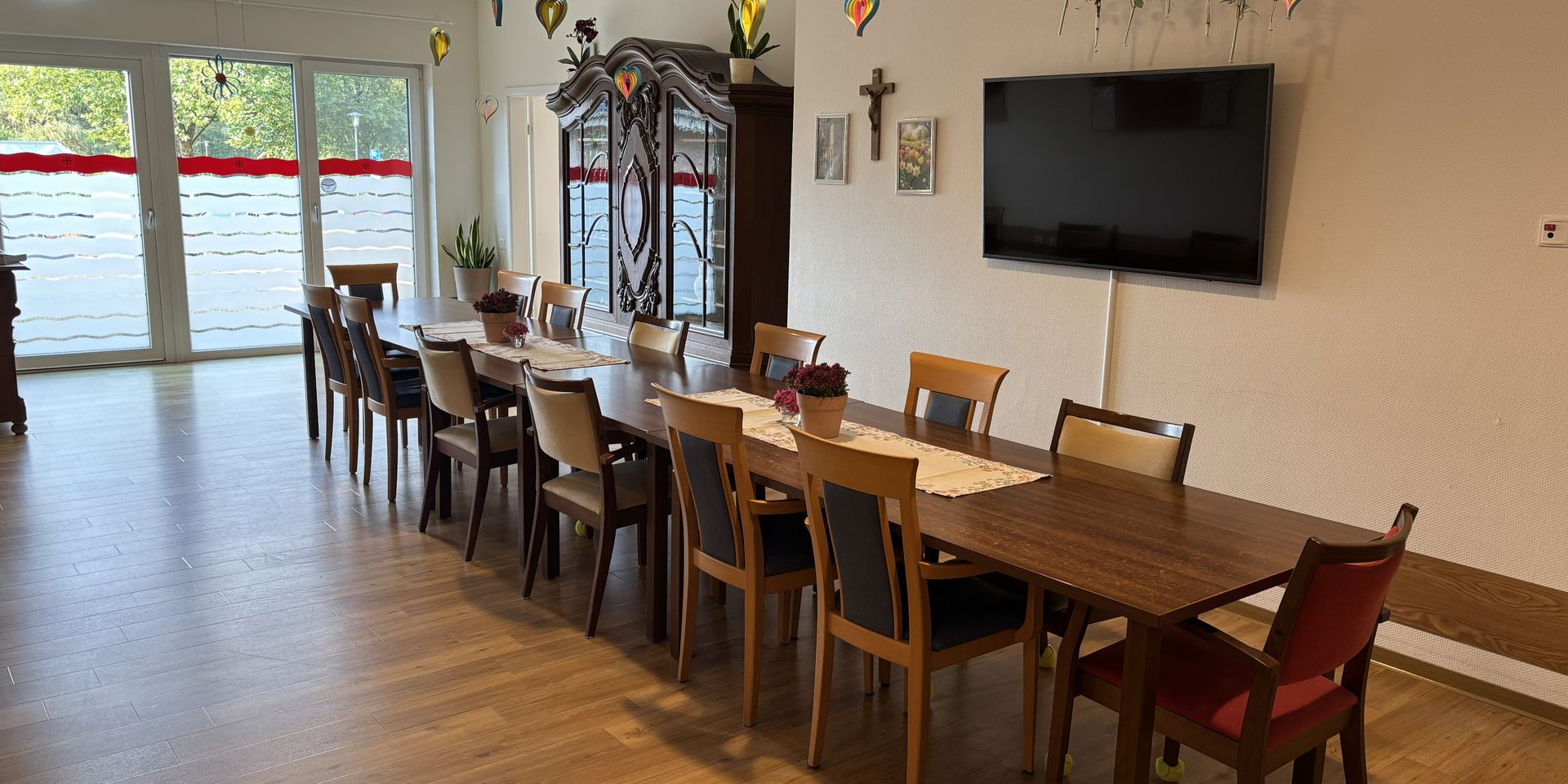 Wohnbereich mit Tischen und Stühlen, TV an der Wand