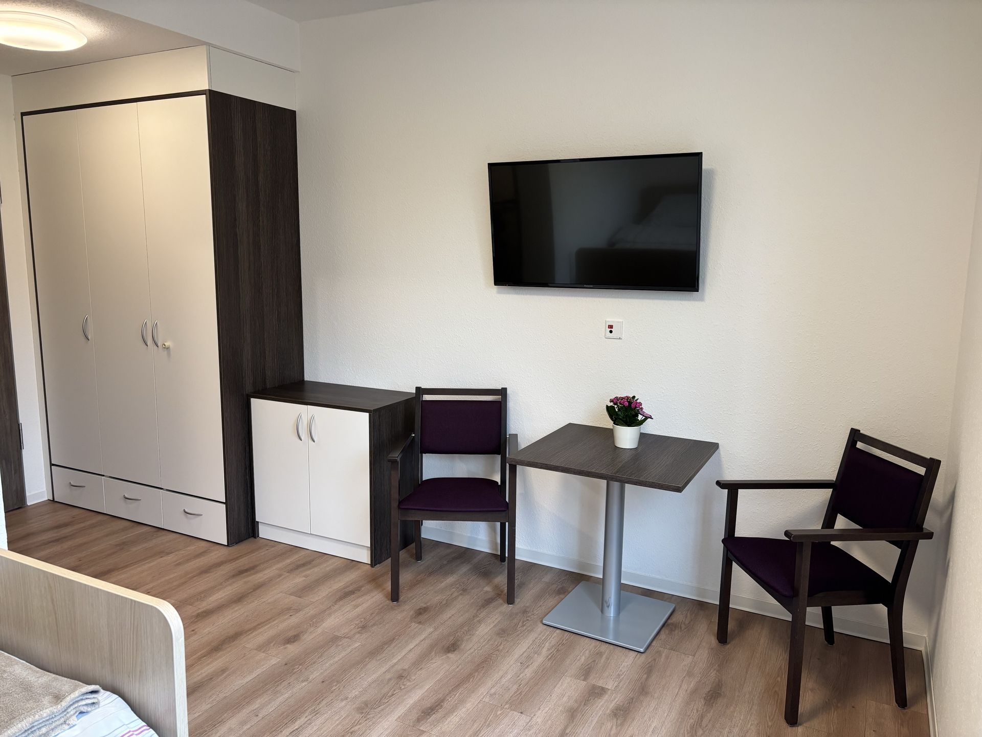 Bewohnerzimmer mit Schränken, Sitzecke und TV