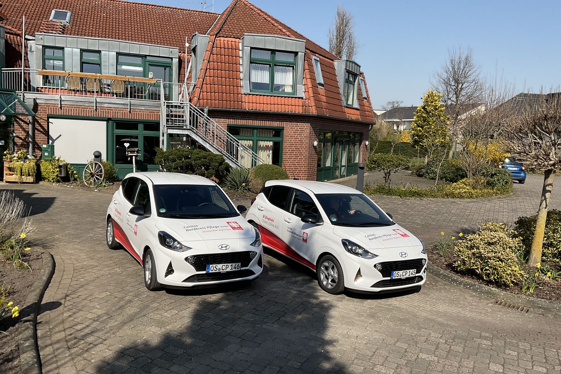 2 weiße Caritas Autos vor einem Gebäude