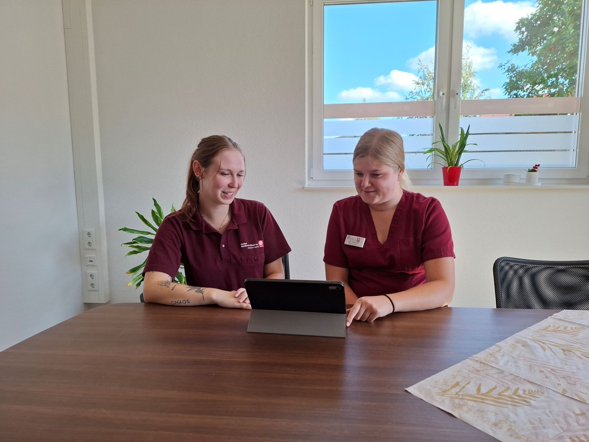 Zwei Frauen sitzen am Tisch und gucken auf ein iPad