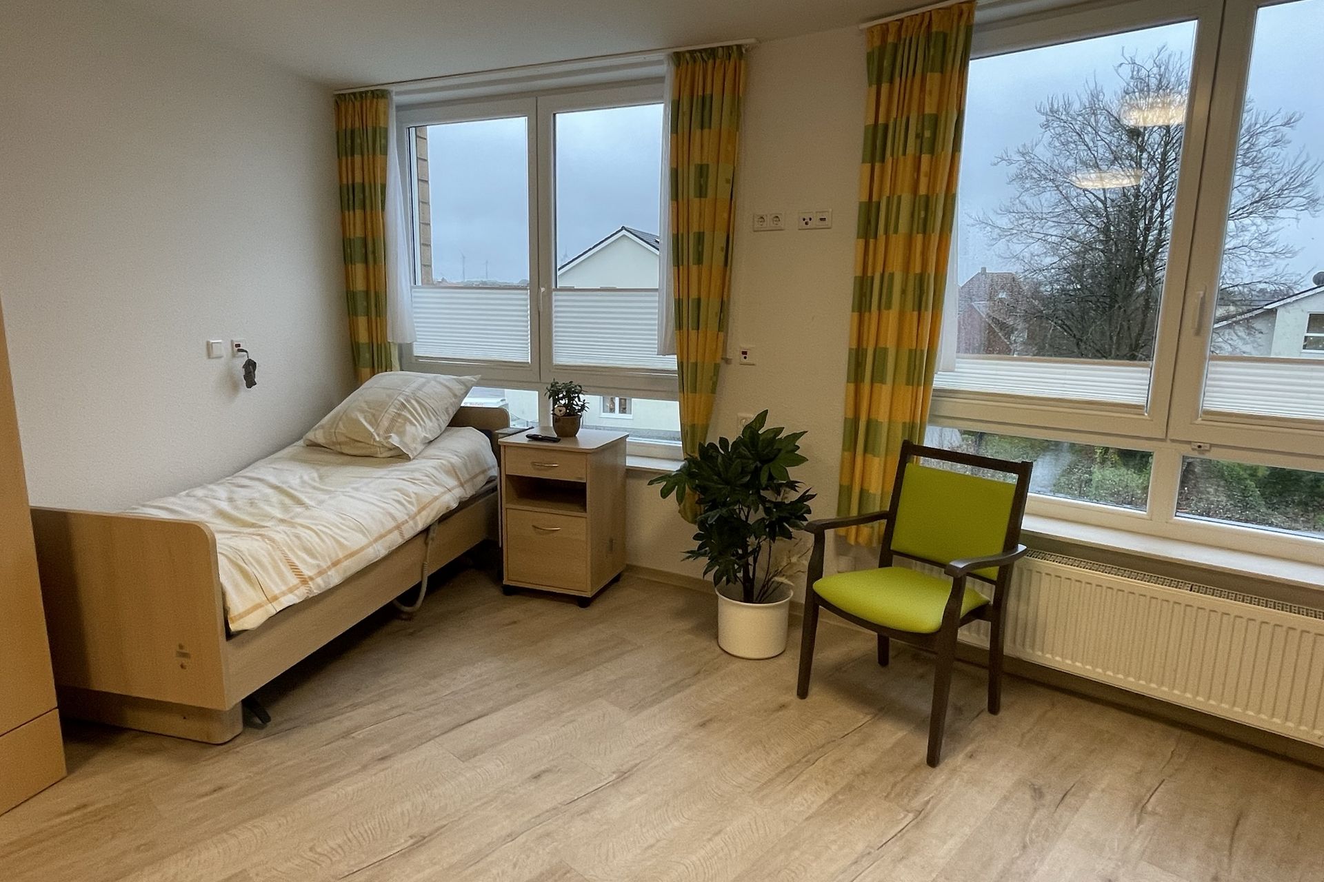 Ein Zimmer mit Bett, Nachtschrank und Stuhl.