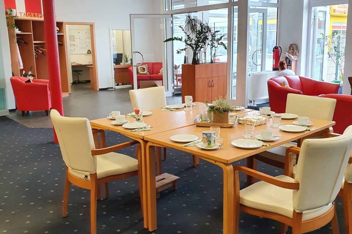 Die Tagespflege von innen. Im Vordergrund ein gedeckter Tisch mit Stühlen.