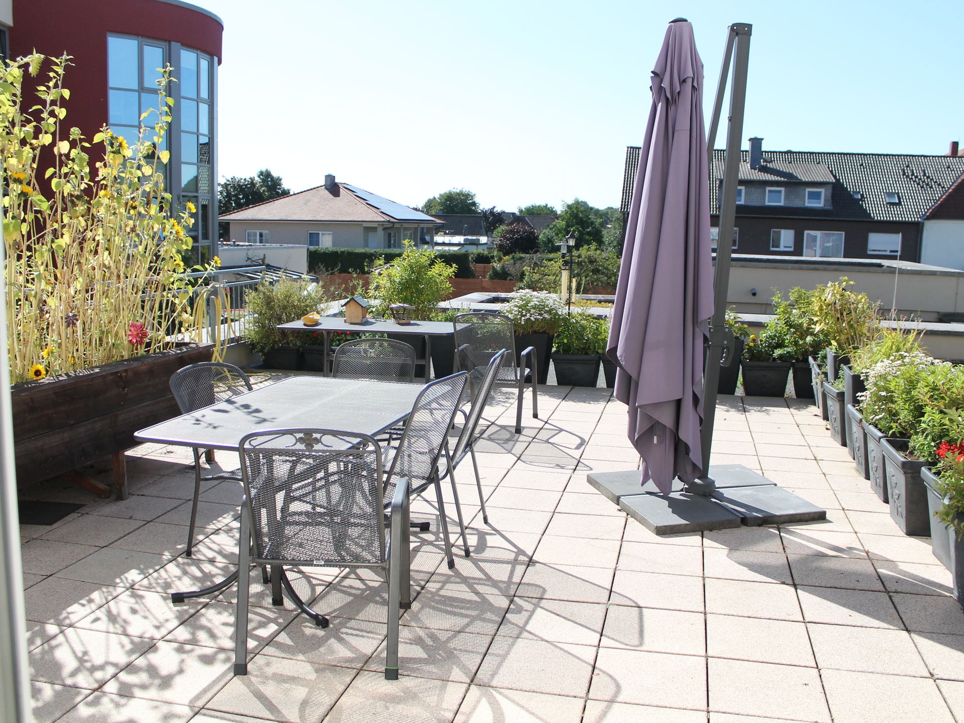 Terrasse im 1. OG. Sitzgruppen, Sonnenschirme und Blumen zusehen.